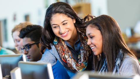 teacher helping students in computer lab